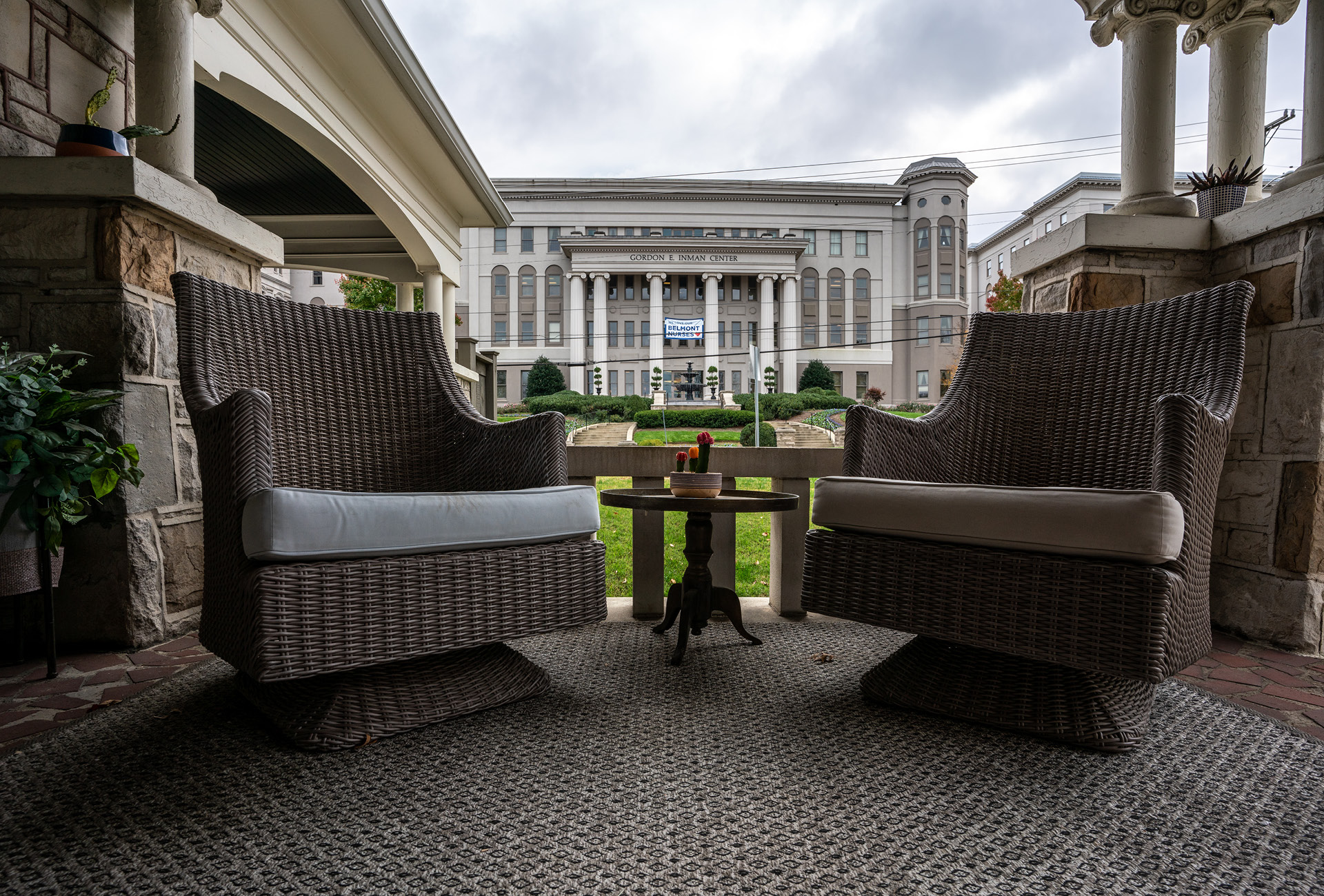 A cozy front porch with two chairs and Belmont University in the background