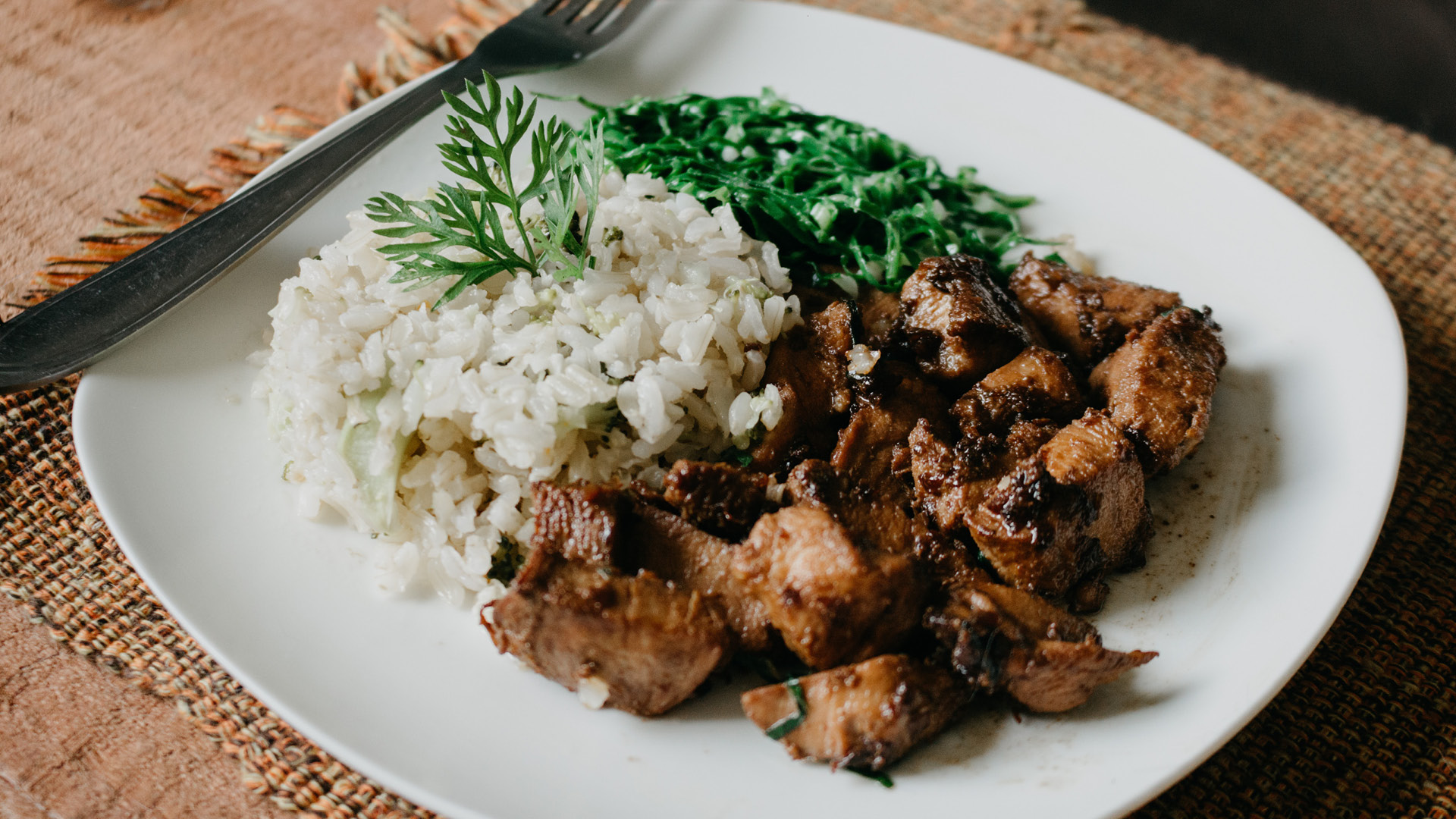 A beautifully prepared plate of chicken, rice, and greens